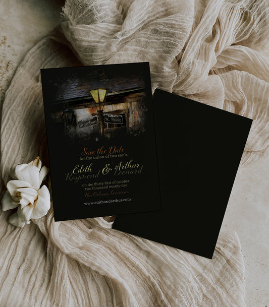 Black New Orleans save the date wedding invitation with an old-style glowing lamppost in the evening at the corner of Bourbon St and St. Phillip with Lafitte's Blacksmith in the background.