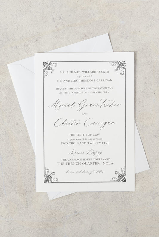 Grey and white wedding invitation with grey damask fleur de lis in the corners and a mix of serif/script fonts in grey.