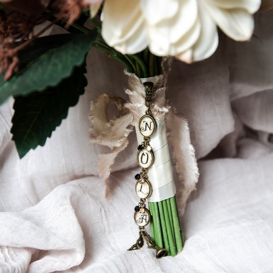 New Orleans wedding Bouquet pendant with the initials N-O-L-A in vintage lettering and a trumpet and mardi gras mask charm.