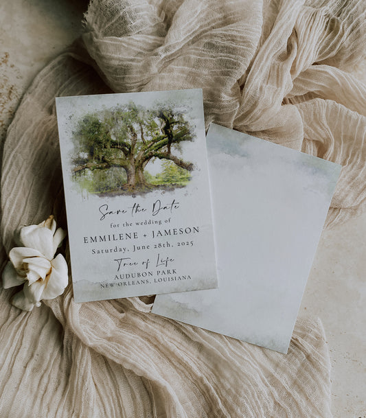 New Orleans save the date featuring a watercolor image of the Tree of Life in Audubon Park. The card has a watecolor splatter background with wedding details written in black.