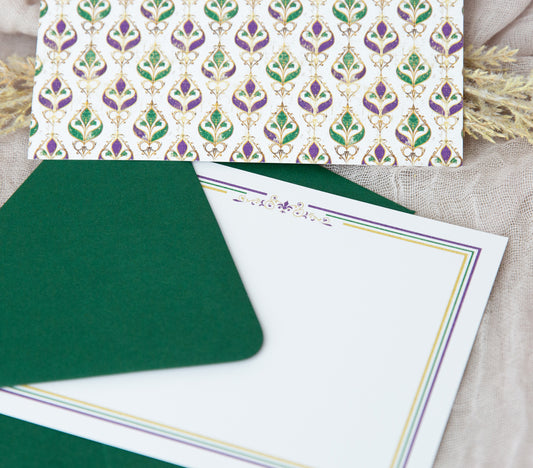 A Touch of Nola stationery notecard featuring Mardi Gras colors of purple, green and gold covered in glitter and fleur de lis.