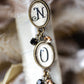 Decorative earrings with 'N' and 'O' charms on a blurred background