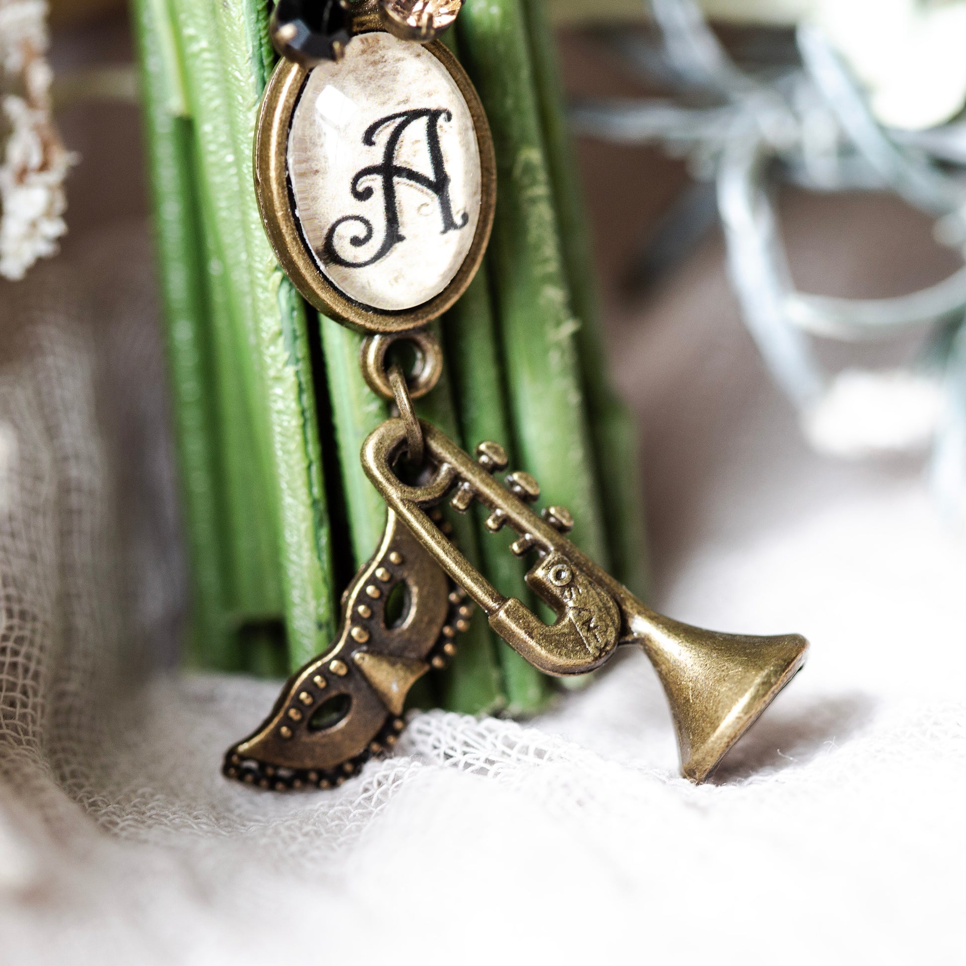 Bronze trumpet-shaped pendant with 'A' on a textured surface