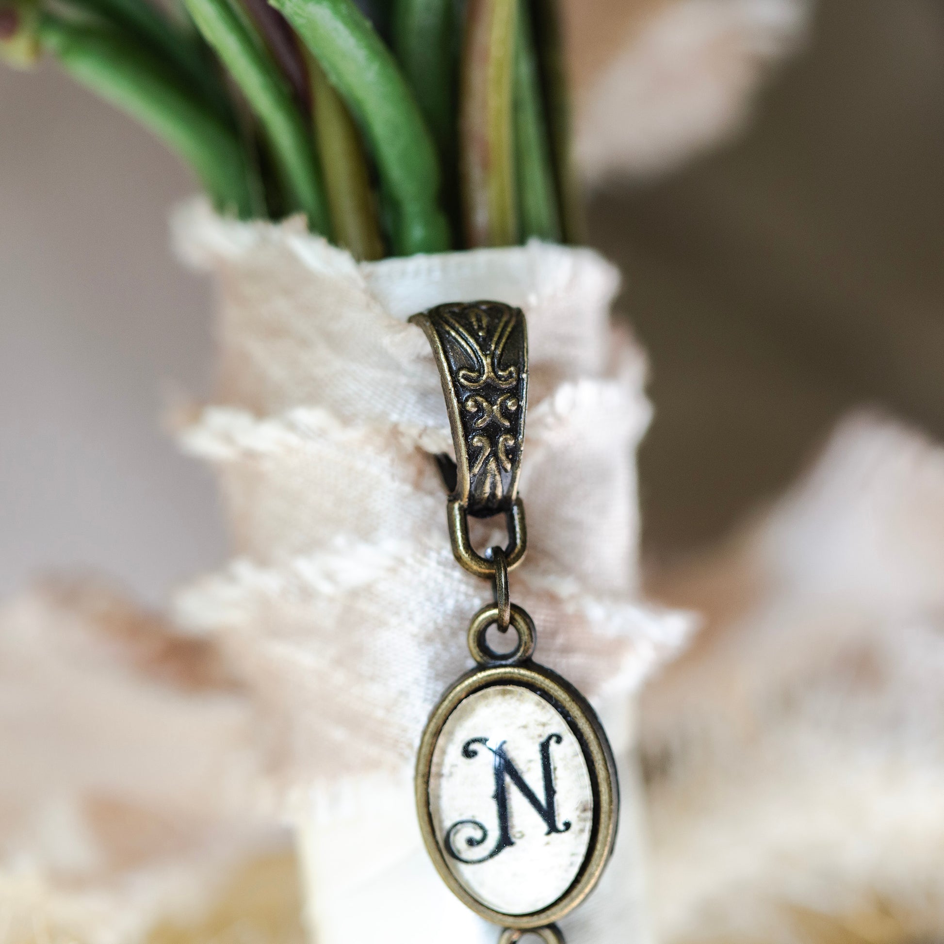 Decorative charm with letter 'N' on a blurred natural background