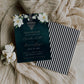 Dark green wedding save the date card with big magnolia's in the top corners and sparkle chandelier in the center. The back is black and white striped to resemble The Parlor's sign on the front of the building.